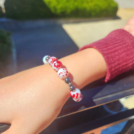 Close-up of a wrist wearing a colorful beaded bracelet with a blurred outdoor background.